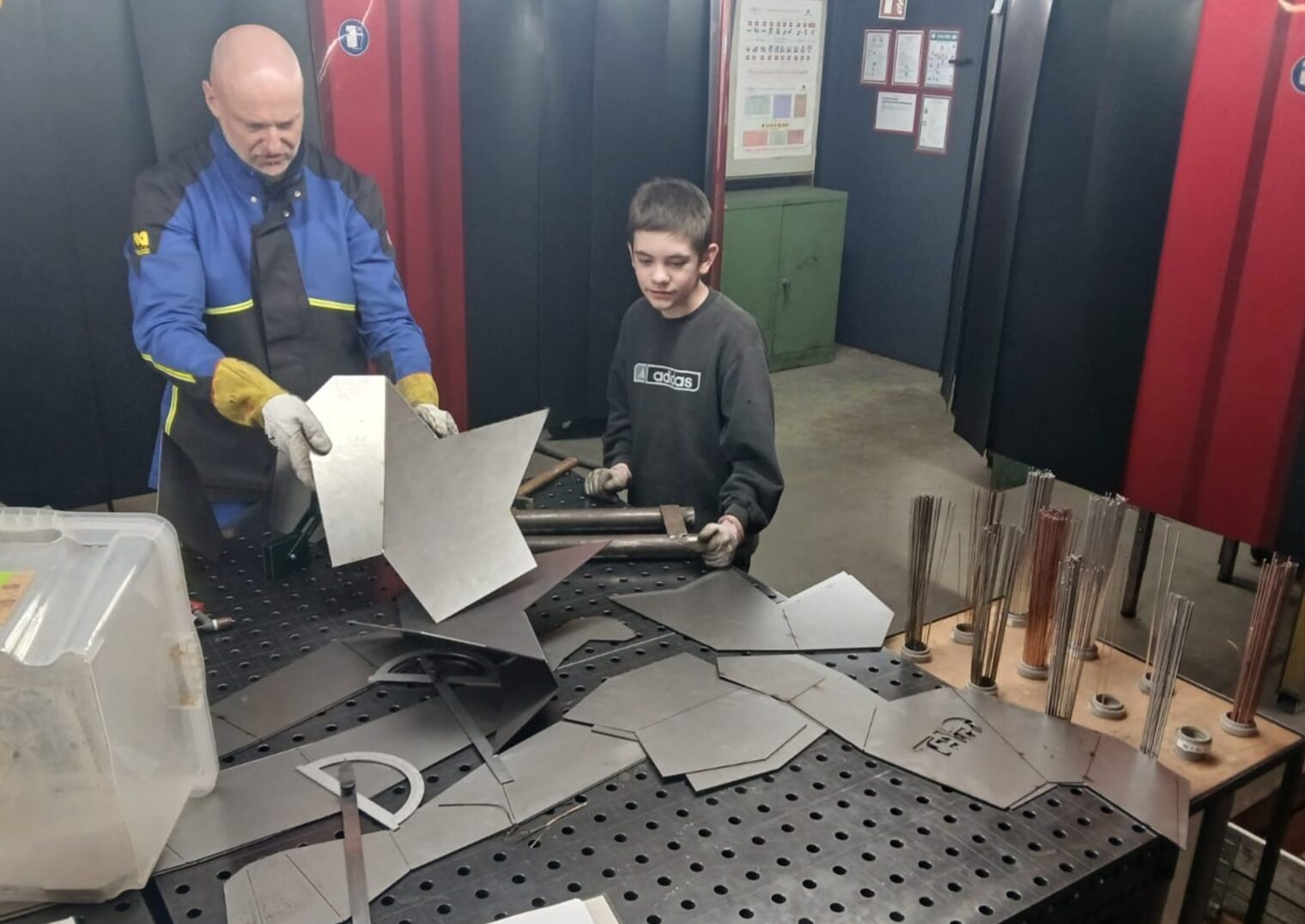 Vorbereitungsarbeiten für das Gorilla‑Schweißprojekt: Ein junger Helfer und Schweißlehrmeister Dirk Schwäble beim Sortieren und Zusammenbau der Metallteile