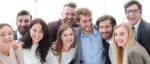Gruppe von Personen steht eng zusammen und blickt in die Kamera.